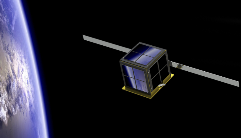 small mirrored PocketQube satellite floating in space high above the earth in the background