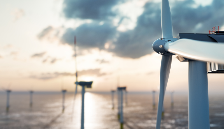 a white wind turbine in the middle of the ocean at sunset, with wind farm out of focus in the background